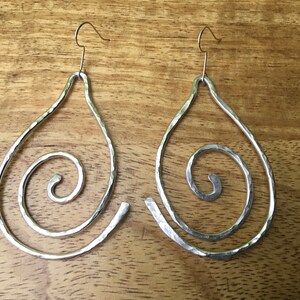 May include: A pair of silver teardrop-shaped earrings with a hammered texture and a spiral design.