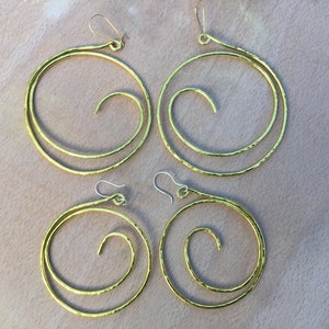 May include: Four gold-toned hammered metal hoop earrings with a spiral design. The earrings are in two different sizes.