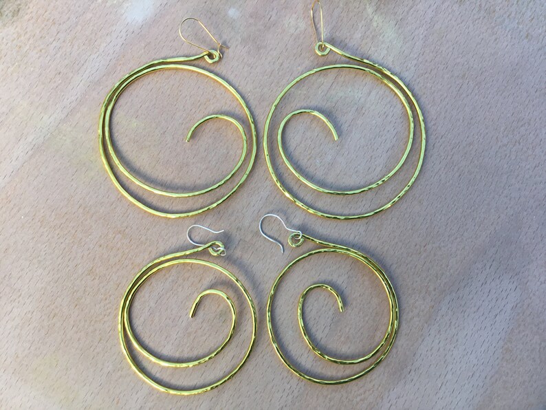 May include: Four gold-toned hammered metal hoop earrings with a spiral design. The earrings are in two different sizes.