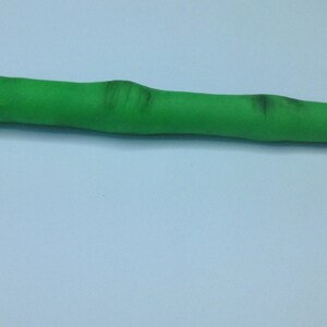 May include: A green finger-shaped pen with a red nail on the end.