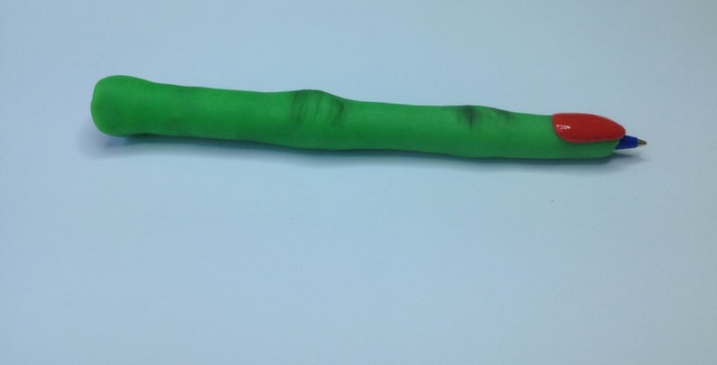 May include: A green finger-shaped pen with a red nail on the end.