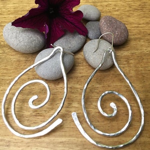 May include: A pair of silver teardrop-shaped earrings with a hammered finish and a spiral design.