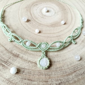 May include: A green macrame necklace with white gemstone beads. The necklace has a teardrop-shaped pendant with a white gemstone.