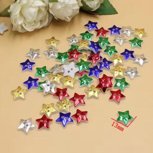 May include: A selection of star-shaped buttons in a variety of colours, including red, green, blue, silver, and gold. Each button measures approximately 1.3 cm across. These decorative buttons are suitable for sewing and craft projects.