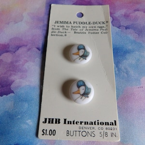 May include: Two Jemima Puddle-Duck buttons on a white card. Each button features a duck wearing a blue bonnet. The card reads "JEMIMA PUDDLE-DUCK" and "BUTTONS 5/8 IN."