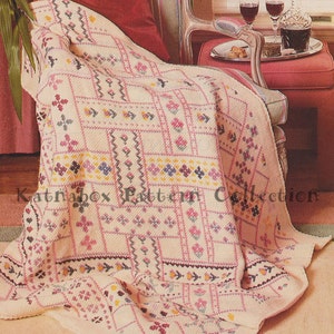 May include: A crocheted throw blanket with a floral pattern in shades of pink, yellow, and blue. The blanket is draped over a chair with a red cushion.