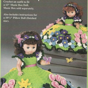 May include: Crochet pattern for a 13-inch music box doll and a 10 1/2-inch pillow doll. The dolls are wearing green dresses with floral accents and butterfly embellishments. The pattern includes instructions for making the dresses and accessories.