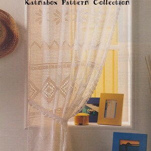 Könnte beinhalten: Weiße Häkelvorhänge mit einem zarten Muster hängen an einem Fenster. Die Vorhänge sind mit einem Knoten zurück gebunden. Der Text "Katnäbox Pattern Collection" ist oben im Bild sichtbar.