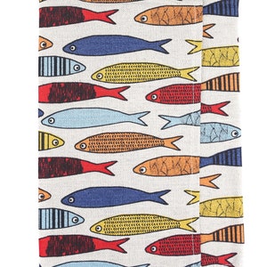 May include: A white fabric placemat with a colorful fish pattern. The fish are in various colors, including red, orange, yellow, blue, and black. The fish are all facing the same direction and have a simple, stylized design.