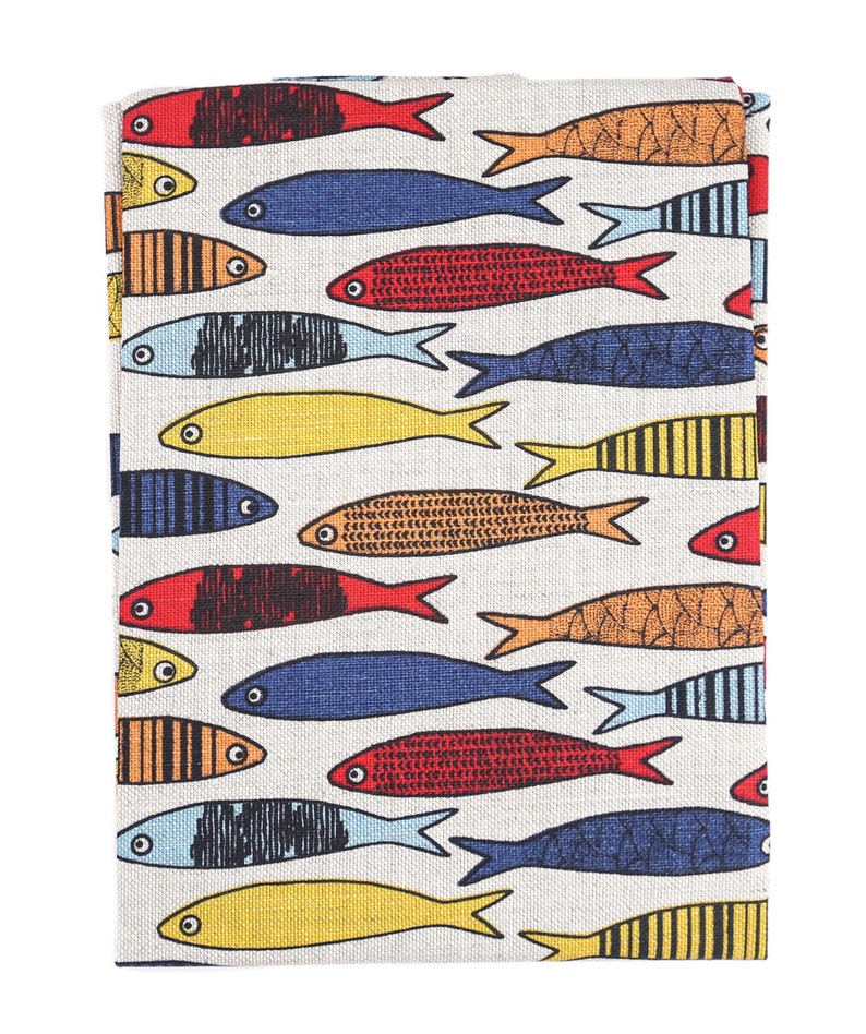 May include: A white fabric tea towel with a repeating pattern of colorful fish. The fish are in shades of red, blue, yellow, and orange.