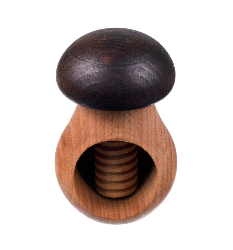 May include: A wooden nutcracker shaped like a mushroom with a dark brown top and a light brown base. The nutcracker has a threaded screw in the center.