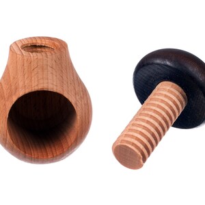 May include: A wooden nutcracker with a pear-shaped base and a threaded screw with a dark brown knob. The nutcracker is made of light wood and has a hole in the base for cracking nuts.