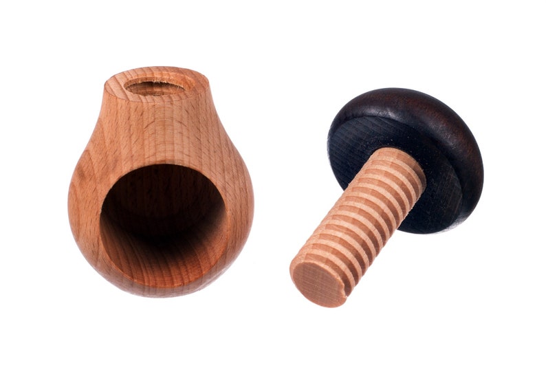 May include: A wooden nutcracker with a pear-shaped base and a threaded screw with a dark brown knob. The nutcracker is made of light wood and has a hole in the base for cracking nuts.