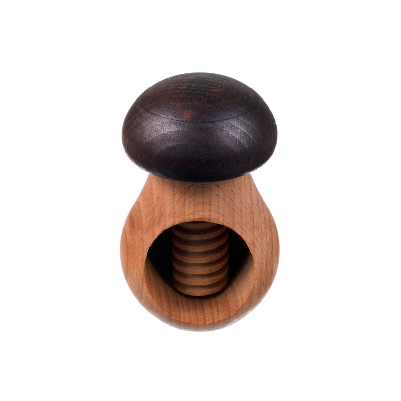 May include: A wooden nutcracker shaped like a mushroom with a dark brown top and a light brown base. The nutcracker has a threaded screw in the center.