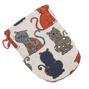 Pode incluir: Uma luva de forno bege com uma borda vermelha e um padrão de gatos coloridos. Os gatos estão em várias poses e têm diferentes cores de pêlo.