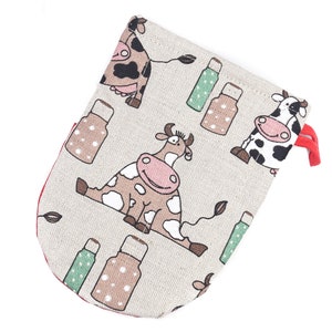 May include: A beige fabric pouch with a red drawstring closure. The pouch is decorated with a repeating pattern of brown and black cows and green and brown milk bottles.