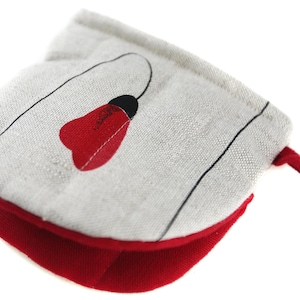 Puede incluir: Un agarrador de olla rojo y blanco con un diseño de flor negro y rojo. El agarrador de olla está hecho de una tela suave y texturizada y tiene un borde rojo.