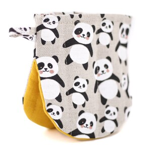 Puede incluir: Un guante de horno gris y blanco con estampado de osos panda. El guante tiene un forro amarillo y un lazo para colgar.