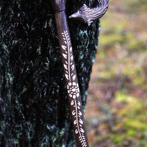 May include: A wooden walking stick with a carved wolf head handle and a white floral design.