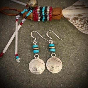 May include: Silver dangle earrings with turquoise and gold beads and a buffalo nickel charm.