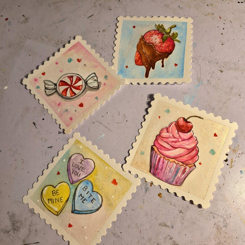 K&ouml;nnte beinhalten: Aquarellillustrationen von S&uuml;&szlig;igkeiten auf Postkarten in Briefmarkenform. Die Karten zeigen ein Bonbon, eine schokoladen&uuml;berzogene Erdbeere, einen Cupcake mit Kirsche und Gespr&auml;chsherzen mit S&auml;tzen wie "Be Mine" und "I Love You".