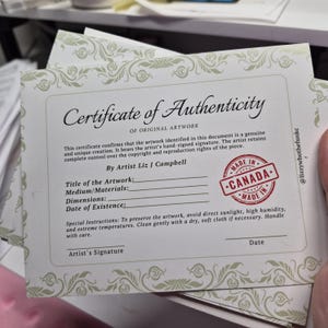 K&ouml;nnte beinhalten: Ein Stapel Echtheitszertifikate f&uuml;r Originalkunstwerke. Die Zertifikate haben einen dekorativen Rand und enthalten den Text "Certificate of Authenticity" und einen Stempel "Made in Canada". Der K&uuml;nstler ist Liz J Campbell.