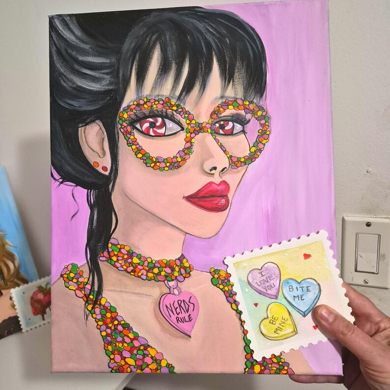 K&ouml;nnte beinhalten: Ein Pop-Art-Gem&auml;lde einer Frau mit zucker&uuml;berzogenen Brillen und einem Halskettenanh&auml;nger mit der Aufschrift "Nerds Rule". Sie h&auml;lt eine Karte mit herzf&ouml;rmigen S&uuml;&szlig;igkeiten mit den Aufschriften "I love you", "Bite me" und "Be mine". Der Hintergrund ist rosa.