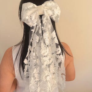 May include: A white lace bow with a satin center, perfect for adding a touch of elegance to any hairstyle.