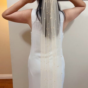 May include: A delicate ivory bridal veil with a single-tier design and scattered gold beads. The veil is made of soft tulle and is perfect for a simple and elegant wedding look.