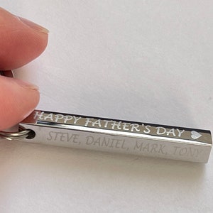 May include: Silver keychain with the inscription "Happy Father's Day" and the names "Steve, Daniel, Mark, Tony" followed by a heart symbol.