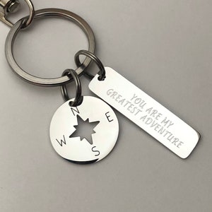May include: Silver keychain with a compass charm and a tag that reads "You are my greatest adventure".