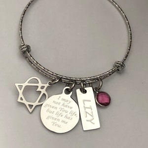 May include: Silver charm bracelet with a star, heart, round charm with the text "I may not have given You life, but life has given me You." and a rectangular charm with the text "LIZY". The bracelet also has a pink gem.