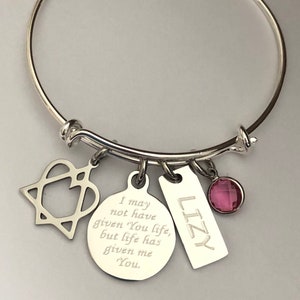 May include: Silver charm bracelet with a heart, a round charm with the text "I may not have given You life, but life has given me You", a rectangular charm with the text "LIZY", and a pink crystal charm.