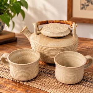 Studio Pottery teservis, krämfärgad ribbad glasyr, tekanna och koppar i rottinghandtag