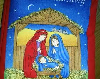 Pode incluir: Um livro vermelho com uma capa azul que representa a cena da natividade. A capa diz "The Christmas Story" com uma lua crescente e estrelas no fundo.