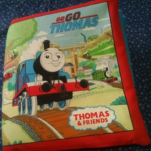 May include: A red, blue and green fabric book featuring Thomas the Tank Engine with the words "Go Go Thomas" and "Thomas & Friends".
