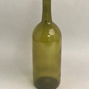 Puede incluir: Una botella de vino vacía de vidrio verde oliva. La botella tiene un cuello largo y un cuerpo redondeado. El vidrio es transparente. La botella está diseñada para contener aproximadamente 750 ml de líquido.