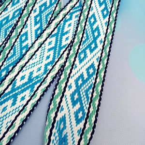 K&ouml;nnte beinhalten: Nahaufnahme eines gewebten Bandes mit wei&szlig;em Hintergrund und einem blauen und gr&uuml;nen geometrischen Muster.