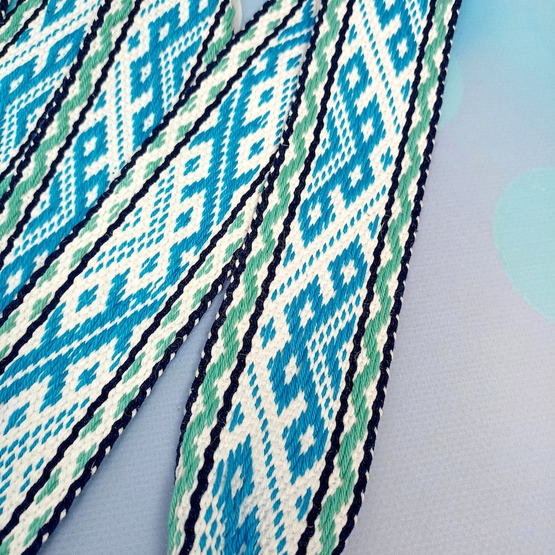 K&ouml;nnte beinhalten: Nahaufnahme eines gewebten Bandes mit wei&szlig;em Hintergrund und einem blauen und gr&uuml;nen geometrischen Muster.