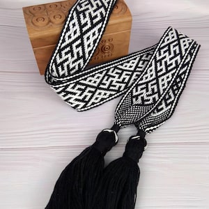 May include: Black and white woven belt with geometric pattern and black tassels.