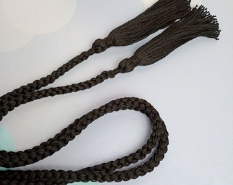 Könnte beinhalten: Eine schwarze geflochtene Schnur mit zwei schwarzen Quasten an den Enden. Die Schnur ist etwa 1 Meter lang.