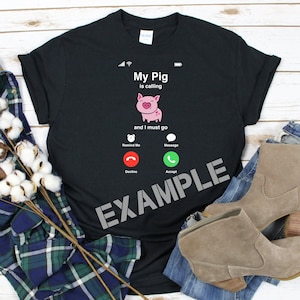 以下が含まれることがあります： 「My Pig」からの電話がかかってきたことを示す電話画面のグラフィックがプリントされた黒いTシャツ。「and I must go」というテキストが表示されています。電話画面には、「電話に出る」、「拒否」、「メッセージ」、「承諾」のオプションが表示されています。