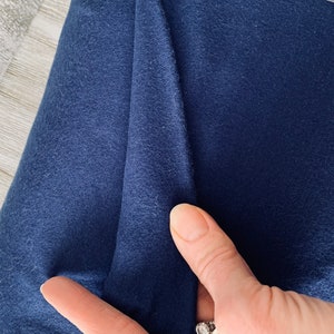 May include: Close-up of a dark blue fabric with a soft, textured surface.