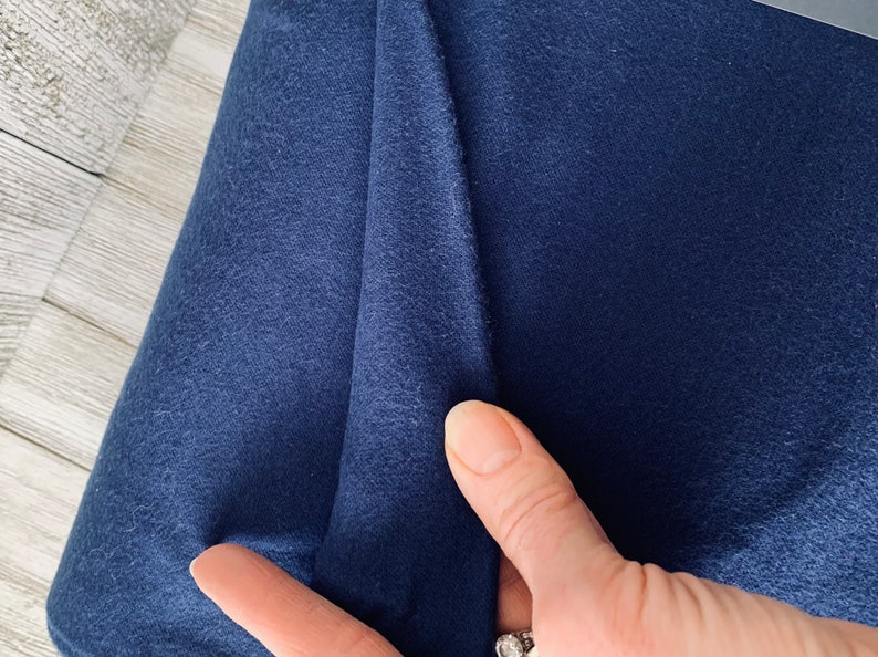May include: Close-up of a dark blue fabric with a soft, textured surface.