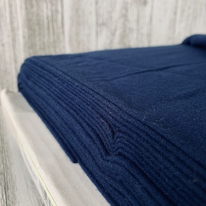 May include: A stack of dark blue fabric folded neatly. The fabric has a soft, textured surface.