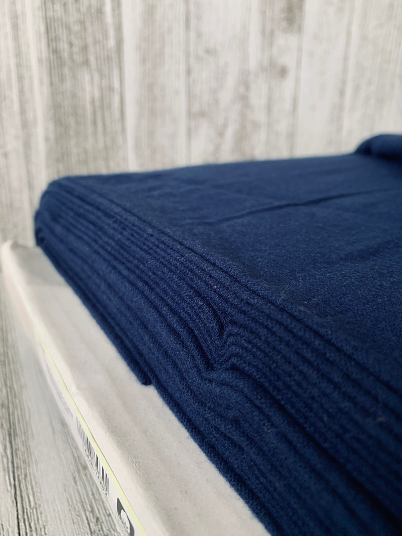 May include: A stack of dark blue fabric folded neatly. The fabric has a soft, textured surface.