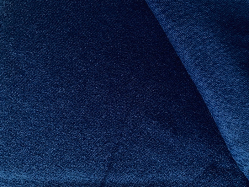 May include: Close-up of a dark blue fabric with a textured, corduroy-like surface.