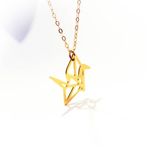 May include: A gold origami crane pendant necklace. The crane is a symbol of peace and good luck.
