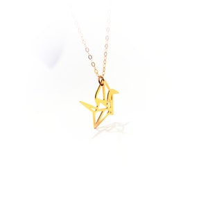 May include: A gold origami crane pendant necklace. The crane is a symbol of peace and good luck.