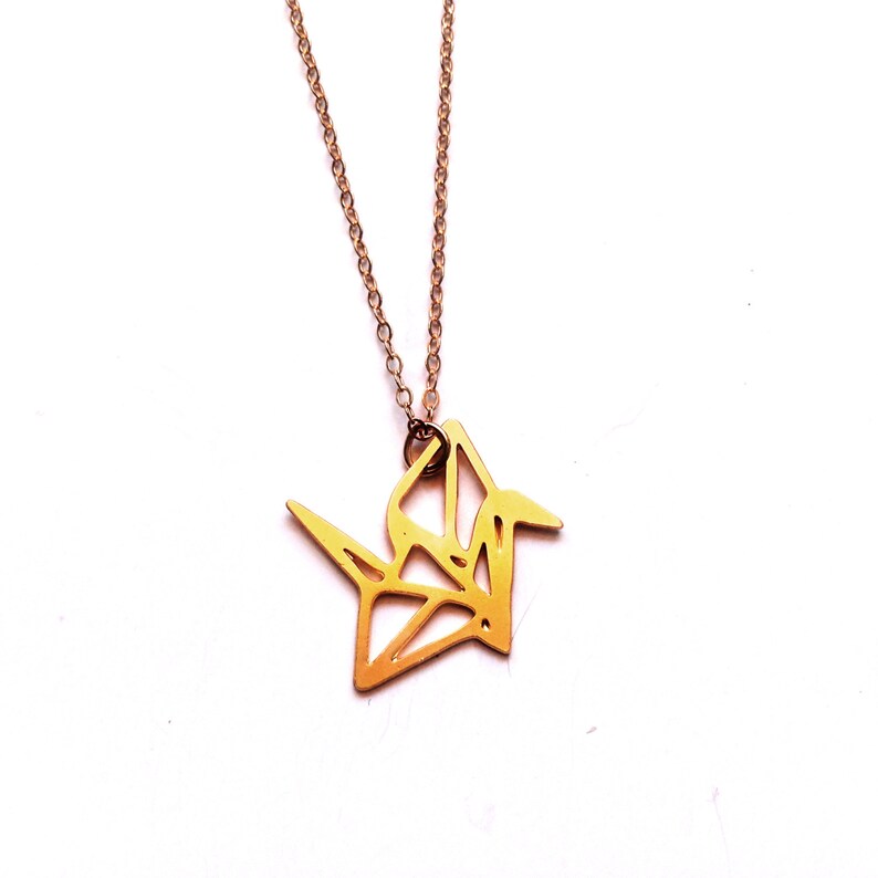 May include: A gold origami crane pendant necklace. The crane is a symbol of peace and good luck.